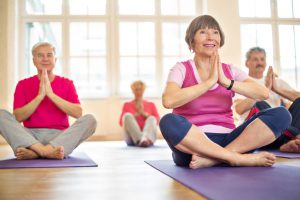 Group of happy seniors practising yoga at health club